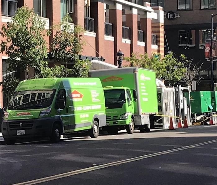 green SERVPRO trucks parked outside of large high rise condo in downtown san diego