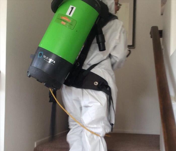 woman in ppe suit with backpack vacuum walking up stairs