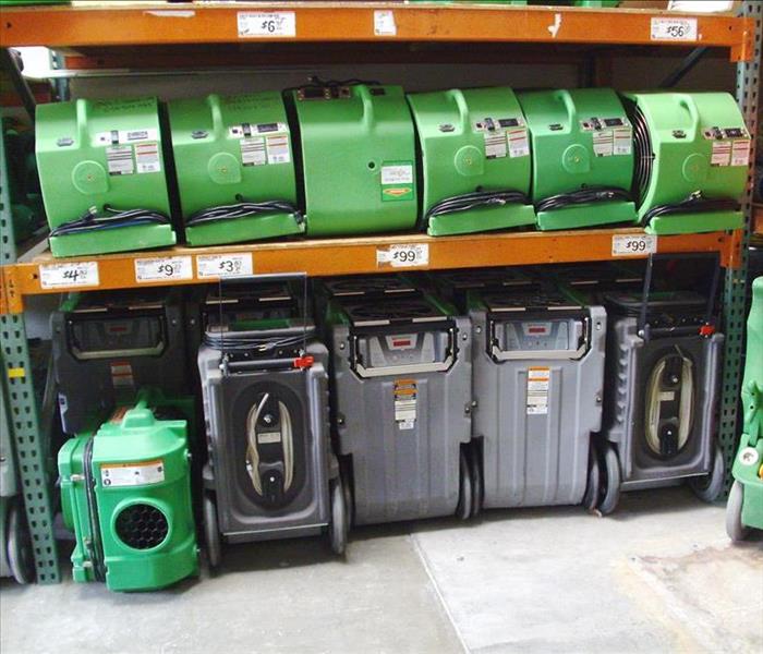 equipment of dehumidifiers and air movers lined up on shelves in warehouse